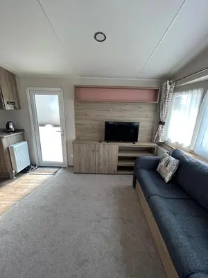 a living room with a couch and a flat screen tv at CaravanSleeps4-Beachfront-Garden-Patio in Newquay