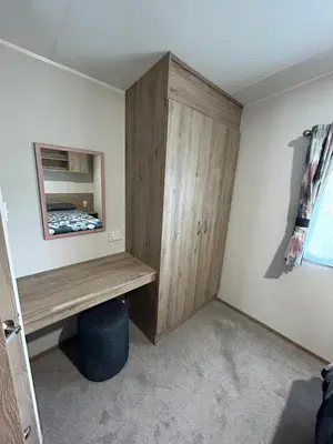 a room with a wooden cabinet and a mirror at CaravanSleeps4-Beachfront-Garden-Patio in Newquay