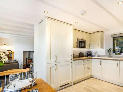 a kitchen with white cabinets and a table with wine glasses at 2 Bed in Fowey oc-86873 in Saint Veep