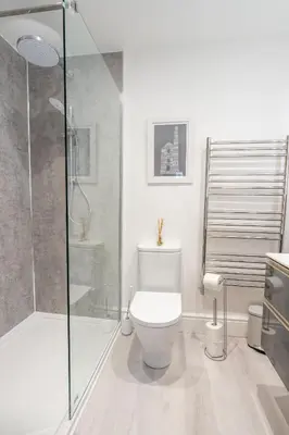 a bathroom with a toilet and a glass shower at Porthleven B and B in Helston