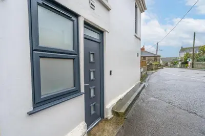 a black door on a white building with a street at Porthleven B and B in Helston