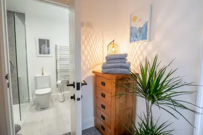 a bathroom with a toilet and a dresser with towels at Porthleven B and B in Helston