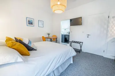 a bedroom with two white beds and a kitchen at Porthleven B and B in Helston