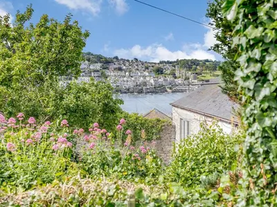 a view of the water from a garden with pink flowers at 3 Bed in Polruan oc-pc012 in Polruan