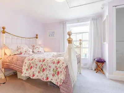 a bedroom with a bed with a floral bedspread and a window at 3 Bed in Polruan oc-pc012 in Polruan