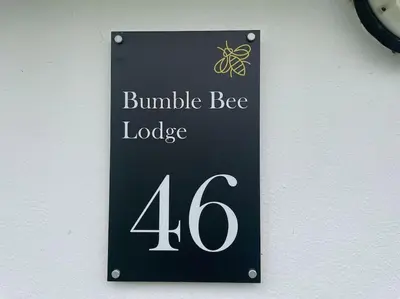 a sign for a bumble bee lodge on a wall at BumbleBee Lodge in Saint Cleer
