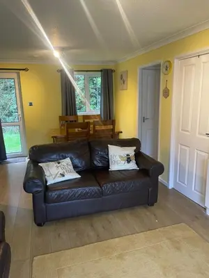 a black leather couch in a living room with a table at BumbleBee Lodge in Saint Cleer