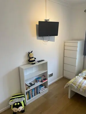 a bedroom with a white book shelf with a tv on the wall at BumbleBee Lodge in Saint Cleer