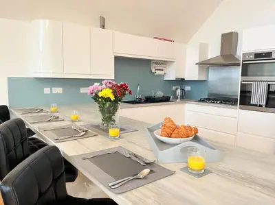 a kitchen with a long table with a vase of flowers at Caledonian House - Newquay in Newquay