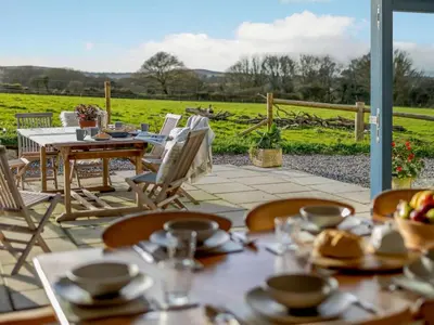 a patio with tables and chairs and a view of a field at 4 Bed in Helston oc-90391 in Crowan