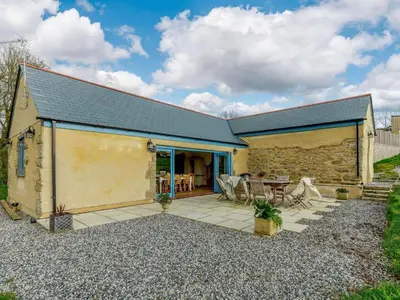 a barn conversion with a stone wall and a patio at 4 Bed in Helston oc-90391 in Crowan