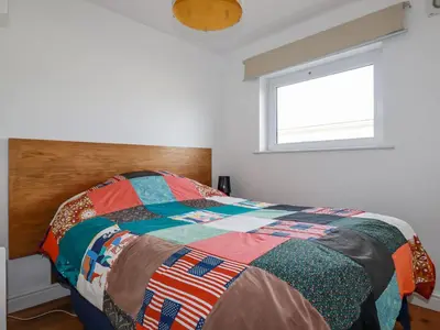 a bedroom with a colorful bed with a window at Lapwing in Perranporth