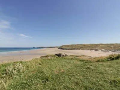 a view of a beach from a hill with grass at Lapwing in Perranporth