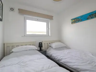two beds in a room with a window at Lapwing in Perranporth