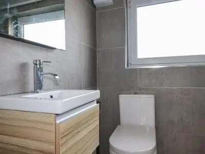 a bathroom with a sink and a toilet and a window at Lapwing in Perranporth