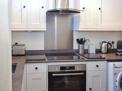 a kitchen with white cabinets and a stove top oven at 2 Bed in Fowey oc-91396 in Fowey