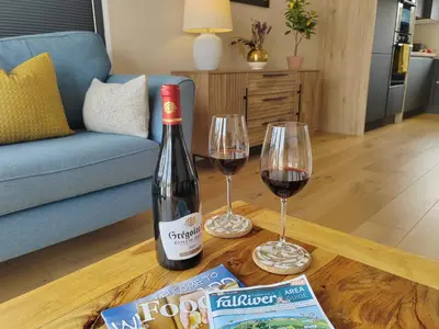 a bottle of wine and two glasses on a table at Modern open plan house, sea views and hot tub in Falmouth