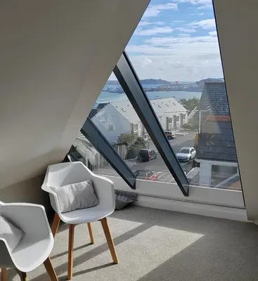 two white chairs in a room with a large window at Modern open plan house, sea views and hot tub in Falmouth