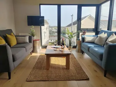 a living room with two couches and a coffee table at Modern open plan house, sea views and hot tub in Falmouth