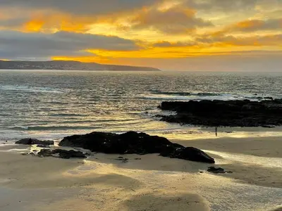 a sunset over the ocean with rocks on the beach at Padstow Lodge in Padstow