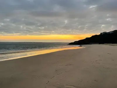 a beach with the sun setting on the water at Sea Breeze - 3 Bed House, Parking for 2 Cars in St Ives