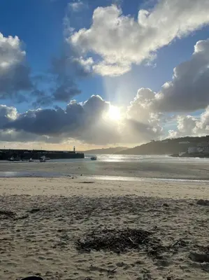 a beach with a cloudy sky and the ocean at Sea Breeze - 3 Bed House, Parking for 2 Cars in St Ives