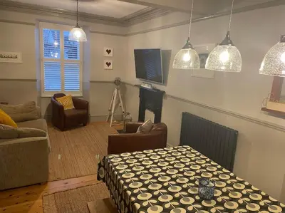 a living room with a couch and a table and pendant lights at Sea Breeze - 3 Bed House, Parking for 2 Cars in St Ives