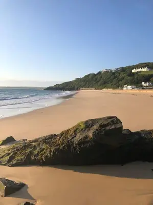 a beach with a large rock in the sand at Sea Breeze - 3 Bed House, Parking for 2 Cars in St Ives