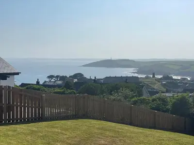 a wooden fence with a view of the ocean at 4 Bed in Fowey oc-91931 in Fowey