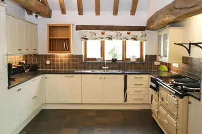 a kitchen with white cabinets and a sink at Beachside holiday home in St Merryn