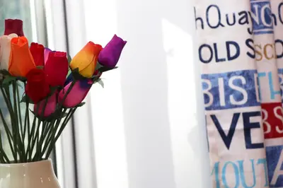 a vase filled with colorful flowers in a window at Beachside holiday home in St Merryn