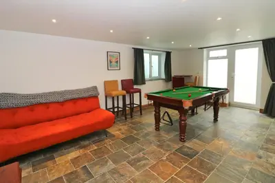 a living room with a couch and a pool table at Beachside holiday home in St Merryn