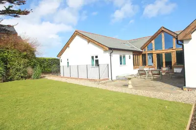 a cottage with a lawn in front of it at Beachside holiday home in St Merryn