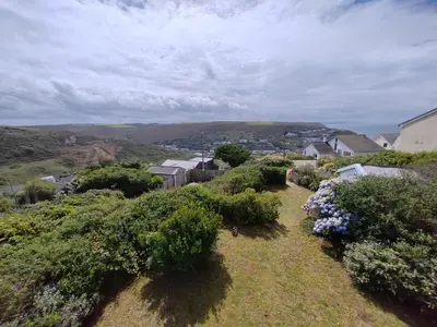 a field with bushes and flowers on a hill at Unique coastal detached property in Truro