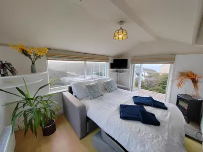 a bedroom with a bed and a couch and a window at Unique coastal detached property in Truro