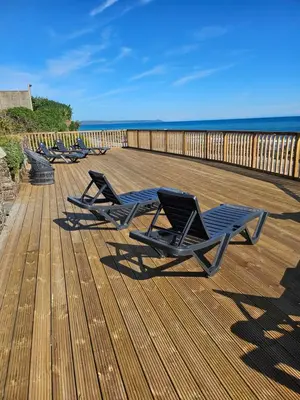 a row of lounge chairs on a deck with the beach at Stunning Front Line Ocean Views Luxury Beach House in Downderry