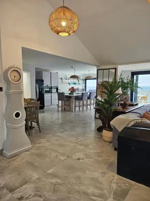 a living room with a clock and a dining room at Stunning Front Line Ocean Views Luxury Beach House in Downderry