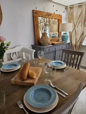 a wooden table with blue plates and wine glasses on it at Stunning Front Line Ocean Views Luxury Beach House in Downderry