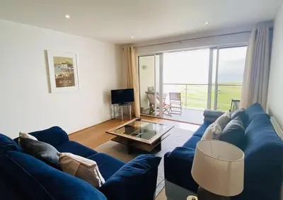 a living room with a blue couch and a glass table at Bredon Court overlooking Fistral beach, Newquay in Newquay