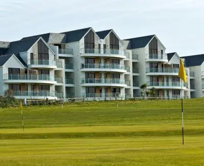 a large building with a green field in front of it at Bredon Court overlooking Fistral beach, Newquay in Newquay
