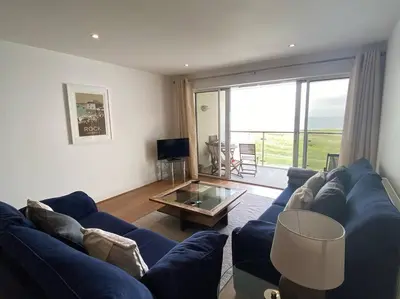 a living room with a blue couch and a glass table at Bredon Court overlooking Fistral beach, Newquay in Newquay