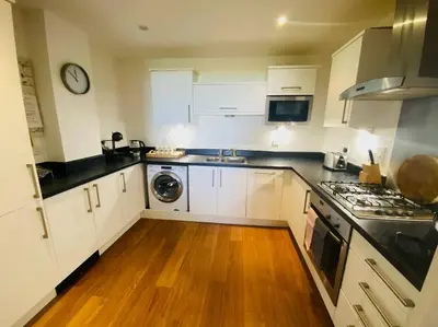 a kitchen with white cabinets and a stove top oven at Bredon Court overlooking Fistral beach, Newquay in Newquay