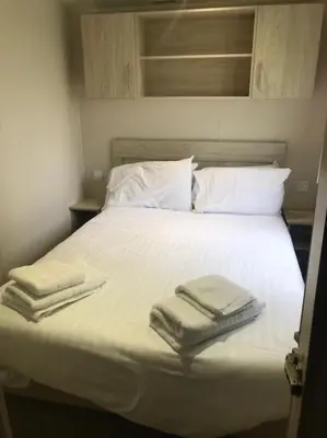 a white bed with two folded towels on it at 2 Bedroom Caravan. Newquay. Cornwall. in Newquay