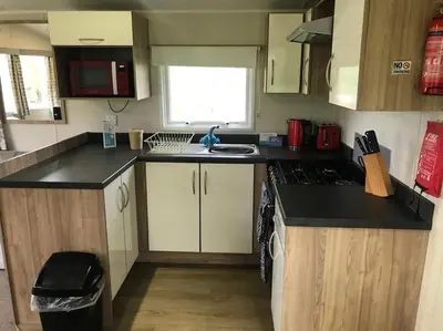a small kitchen with a stove and a sink at 2 Bedroom Caravan. Newquay. Cornwall. in Newquay