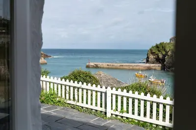 a view of the ocean from a house with a white fence at White House, Port Isaac Bay Holidays in Port Isaac
