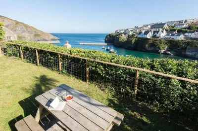 a picnic table sitting on the grass near the ocean at White House, Port Isaac Bay Holidays in Port Isaac