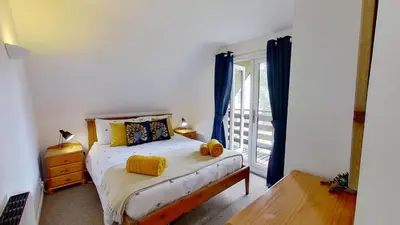 a bedroom with a bed and a window with blue curtains at 45 Trevithick Court, Tolroy Manor in Hayle