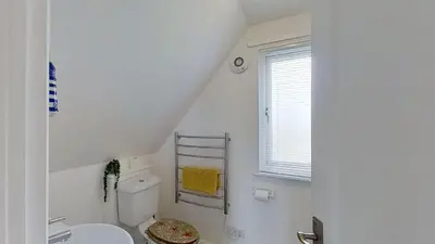 a white bathroom with a toilet and a window at 45 Trevithick Court, Tolroy Manor in Hayle