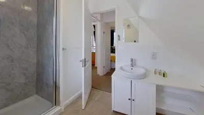 a white bathroom with a shower and a sink at 45 Trevithick Court, Tolroy Manor in Hayle