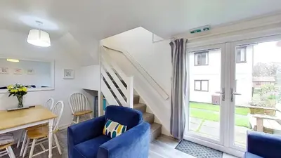 a living room with a blue chair and a staircase at 46 Strawberry Hill, Tolroy Manor in Hayle